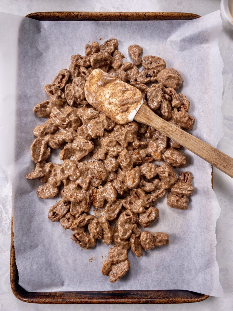 Sugar-free and Keto Candied Pecans being spread out in an even layer on a parchment-lined baking sheet.