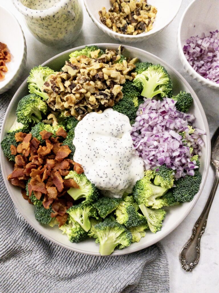 Chopped broccoli florets topped with crumbled bacon, chopped walnuts, diced red onion, and creamy poppy seed dressing.