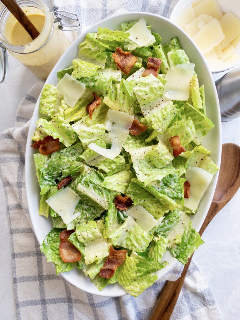 Keto Caesar Salad made with crisp romaine lettuce, chopped bacon, shaved parmesan, and topped with homemade dressing.