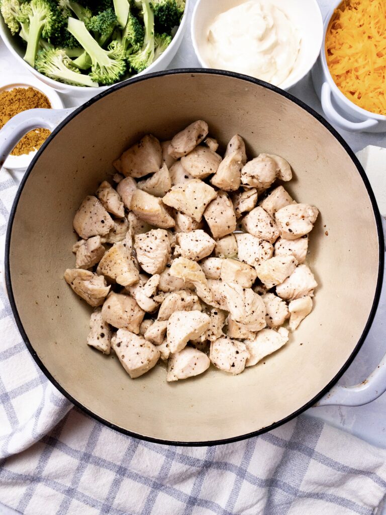 Cubed chicken sauted in an enamelled pan.