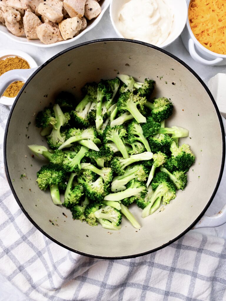 Broccoli florets sauted in an enamelled pan.