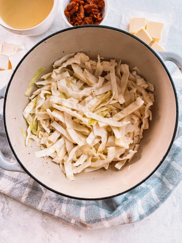 Green cabbage being sauteed in a dutch oven.
