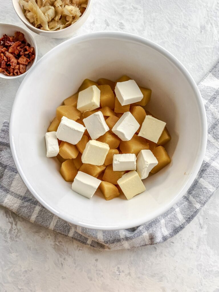 Boiled, cubed rutabaga in a bowl with butter and cream cheese for mashed rutabaga.