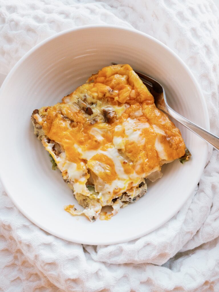 Keto breakfast casserole made with sausage, onion, poblano pepper, and a blend of mozzarella + cheddar cheese.